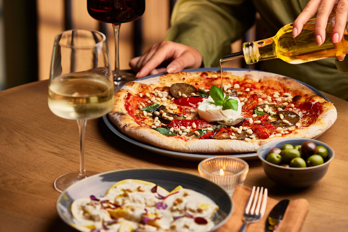 Pouring olive oil on a pizza