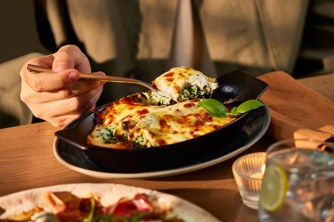 Some one eating cannelloni stuff with ricotta and spinach
